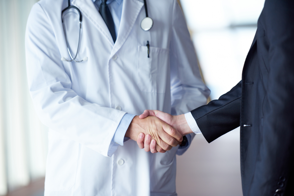 doctor handshake with a patient at doctors bright modern office in hospital doctor handshake with a patient at doctors bright modern office in hospital
